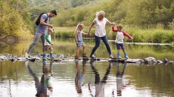 Family crossing a river in the Lake District