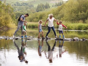 Family crossing a river in the Lake District