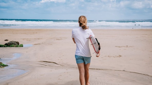 A surfer walking towards the sea