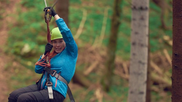 Lady on zipline through forest