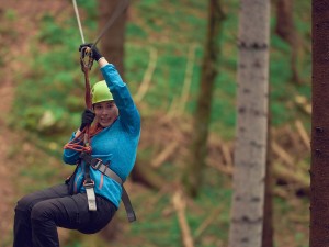 Lady on zipline through forest
